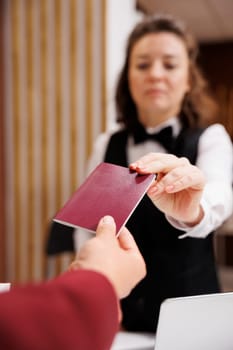 Hotel concierge checks passport, taking identification files from guest to fill in papers and help him settle in. Businessman in suit travelling for corporate work trip. Close up.