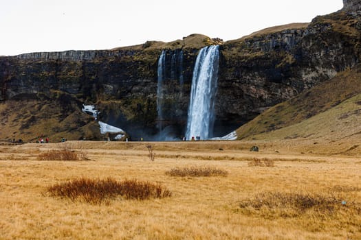 Spectacular waterfall in iceland with stream falling off hills, seljalandsfoss cascade with water flow. Majestic polar icelandic scenery and nordic wilderness, scandinavian frozen land.
