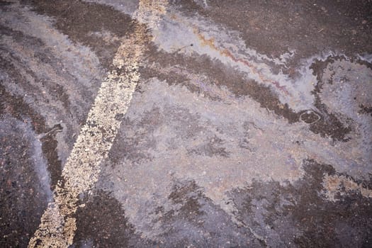 Oil, gasoline, or oil spill on wet asphalt with a parking lot and a dividing line