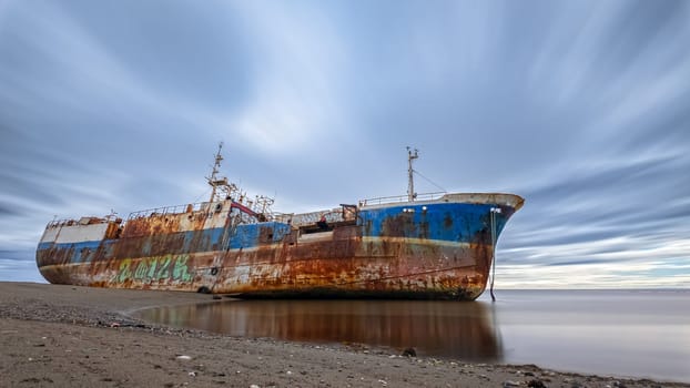 Decaying shipwreck under a changing sky symbolizes lost history and nature's takeover.