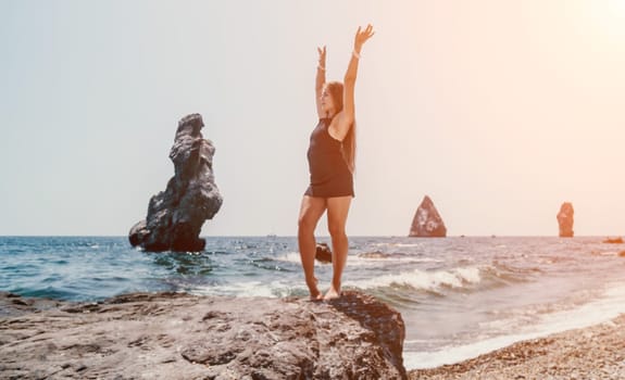 Woman travel sea. Young Happy woman in a long red dress posing on a beach near the sea on background of volcanic rocks, like in Iceland, sharing travel adventure journey