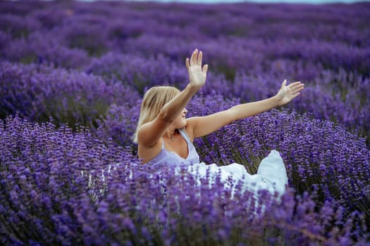 A middle-aged woman sits in a lavender field and enjoys aromatherapy. Aromatherapy concept, lavender oil, photo session in lavender.