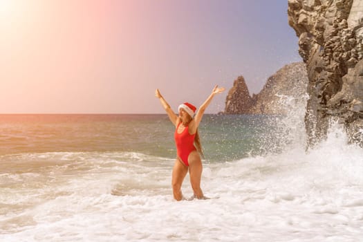 A woman in Santa hat on the seashore, dressed in a red swimsuit. New Year's celebration in a hot country