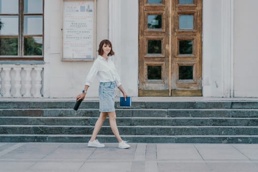 Woman staircase city. A business woman in a white shirt and denim skirt walks down the steps of an ancient building in the city.