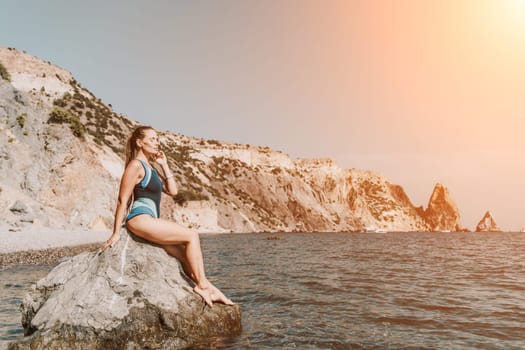 Woman travel summer sea. A happy tourist in a blue bikini enjoying the scenic view of the sea and volcanic mountains while taking pictures to capture the memories of her travel adventure