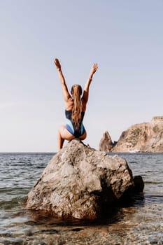 Woman beach vacation photo. A happy tourist in a blue bikini enjoying the scenic view of the sea and volcanic mountains while taking pictures to capture the memories of her travel adventure