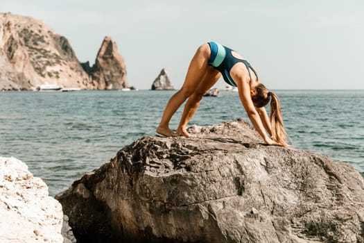 Yoga on the beach. A happy woman meditating in a yoga pose on the beach, surrounded by the ocean and rock mountains, promoting a healthy lifestyle outdoors in nature, and inspiring fitness concept