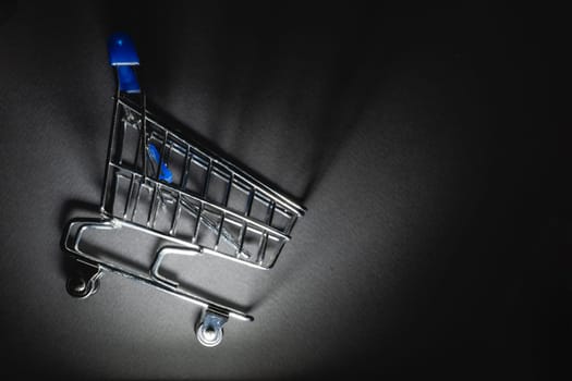 Supermarket cart with spotlight on it on a dark background