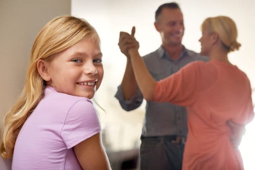 Girl, portrait and smile while parents dance in home, childhood and happy on weekend. Female person, happy couple and love or bonding for fun, smile and calm mindset to relax or confident in joy.