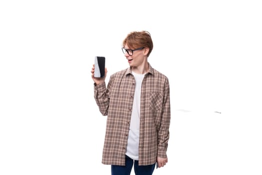 of a cute caucasian student guy in glasses shows the screen of a mobile phone. advertising concept.