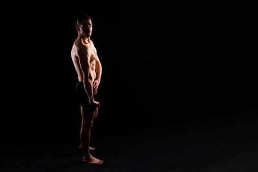 Image of muscle man posing in a studio, dark white red background