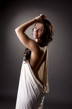Studio shot of lovely model posing in loose-fitting dress