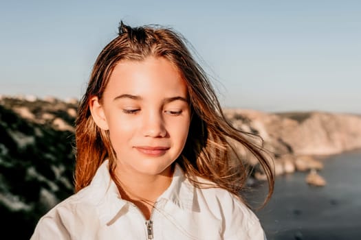 Brown-haired young romantic teenager girl corrects long hair on beach at summer evening wind