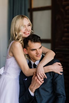 Cute wedding couple in the interior of a classic studio. They kiss and hug each other.