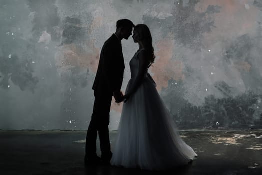 Cute wedding couple in the interior of a classic studio decorated. They kiss and hug each other.