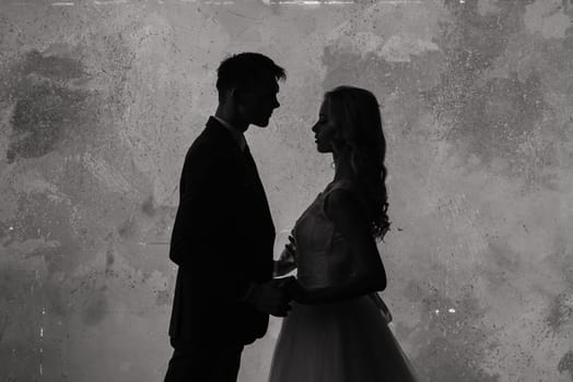 Cute wedding couple in the interior of a classic studio. They kiss and hug each other.