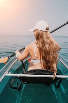 Woman in kayak back view. Happy young woman with long hair floating in transparent kayak on the crystal clear sea. Summer holiday vacation and cheerful female people having fun on the boat.