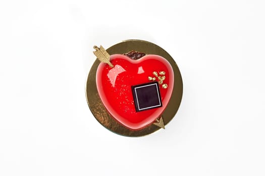Vibrant red heart-shaped strawberry mousse cake with glossy icing, chocolate and gold arrow, perfect for celebrations of love and affection on Valentines Day, top view against white background