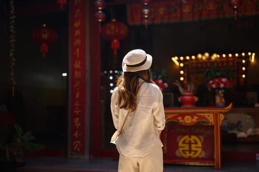 Back view of young woman tourist sightseeing and praying at Chinese Temple in Chang Mai Thailand.