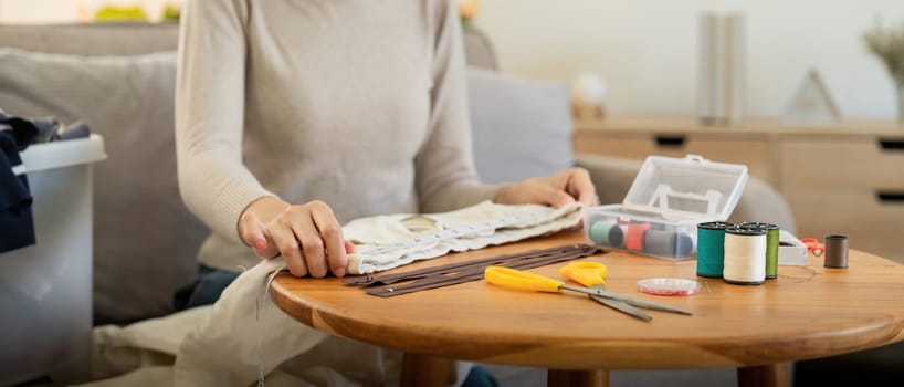 Woman repairs sews reuses fabric from old clothes economical reuse. DIY Hobby Reuse Recycling at home.