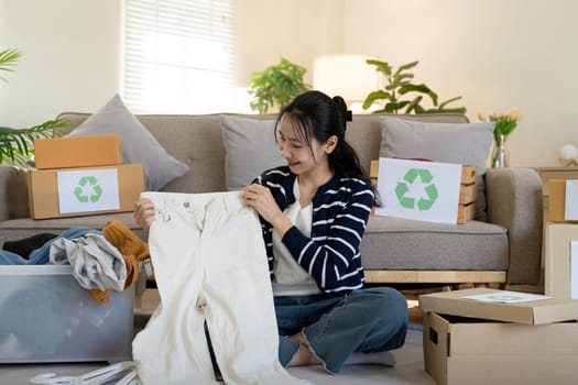 Woman pack box with used clothes for reuse. Reusing, recycling material and reducing waste in fashion, second hand apparel idea. Circular fashion, zero waste concept.