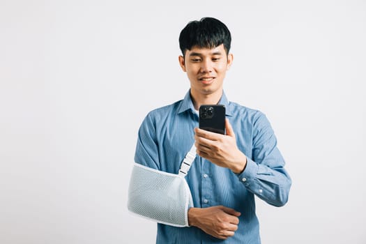 Despite a broken arm, a man wears a splint and handles a smartphone. Happy Asian woman with a sling-supported hand, isolated on white. Social media and copy space included.