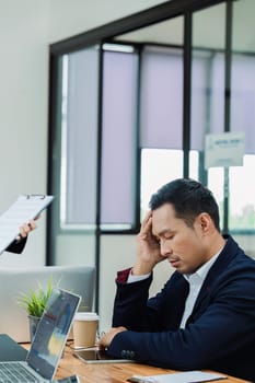 Stressed office employee manager having headache migraine at business meeting with his colleagues about business problem.