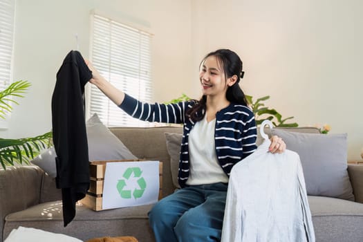 Asian women sort clothes from old clothing box to recycle. Recycling clothes concept.