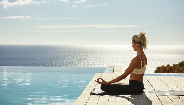 Young woman practicing yoga by a swimming pool with ocean in the background