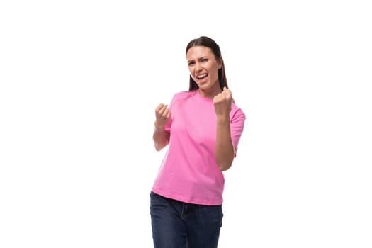 young joyful confident brunette woman in a pink basic t-shirt on a white background with copy space.