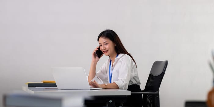 Happy confident businesswoman talking on the phone. Smiling female business person talking work using talking on the phone at office sitting at desk.