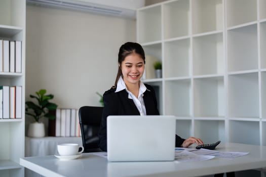 Businesswoman accountant using calculator and laptop for financial data saving in office room, Business financial, tax, accounting concept.