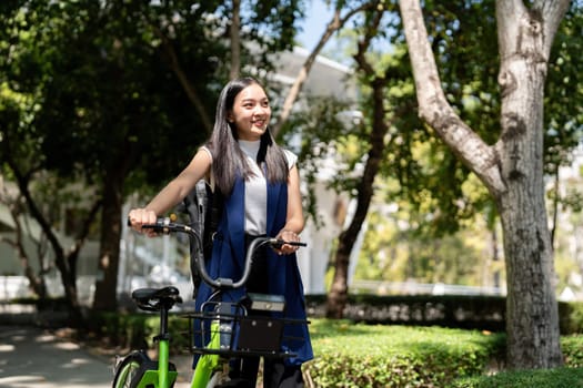 Eco friendly, Happy lifestyle asian beautiful young businesswoman riding bicycle go to office work at city street with bicycle in morning.