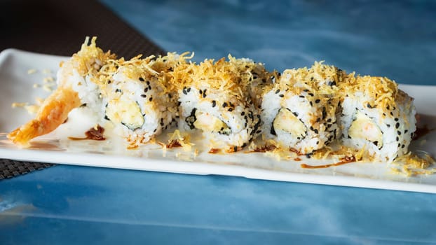 Ebi ten roll, close up view.sushi set with shrimp in tempura, oshinko, garnished with edible flower and black sesame, on an oriental tray, plate at restaurant.