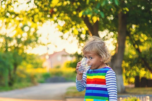 a child drinks water from a glass. Selective focus. Kid.