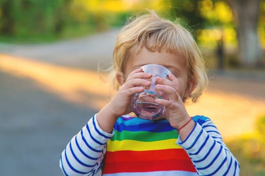 a child drinks water from a glass. Selective focus. Kid.