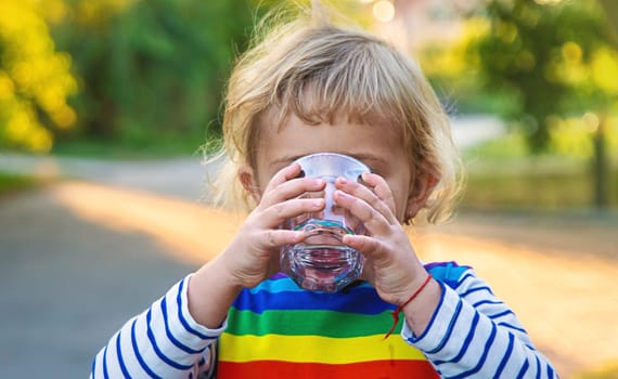 a child drinks water from a glass. Selective focus. Kid.