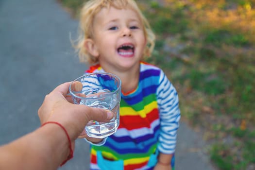 the father gives the child a glass of water. Selective focus. Kid.