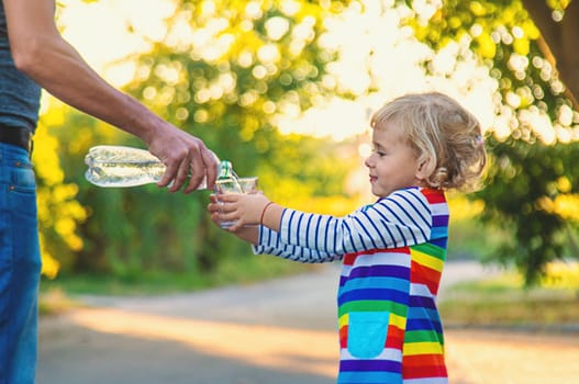 the father gives the child a glass of water. Selective focus. Kid.