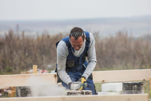 Building working - adult man with circular saw outdoors, small business, telephoto shot