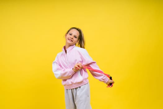 Beautiful sportsgirl with skipping rope isolated on a yellow studio