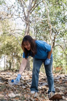 young woman holds a garbage bag and a group of Asian volunteers collect garbage in plastic bags and clean up