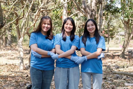 A group of Asian volunteers collects trash in plastic bags and cleaning areas in the forest to preserve the natural ecosystem..