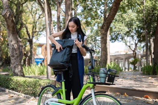 Asian businesswoman ride a bicycle in the city to work outside the city to reduce carbon emissions. Alternative transportation for green energy.