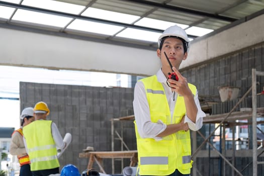 Civil engineer teams meeting working together wear worker helmets hardhat on construction site in modern city. Foreman industry project manager engineer teamwork. Asian industry professional team.