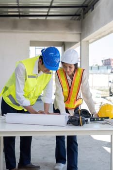 Civil engineer teams meeting working together wear worker helmets hardhat on construction site in modern city. Foreman industry project manager engineer teamwork. Asian industry professional team.