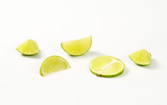 Pieces of fresh lime fruit on white background