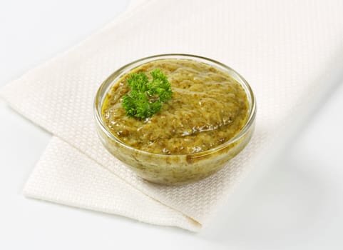 Basil pesto in glass bowl on white napkin