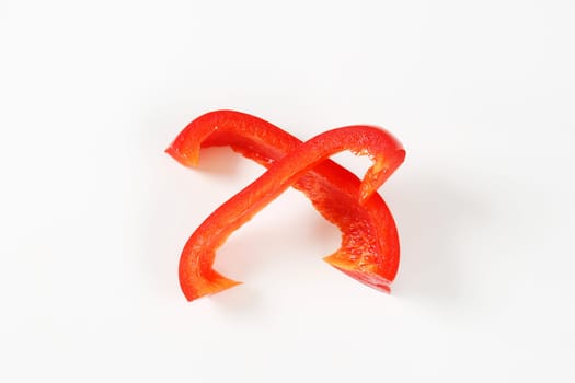 Two slices of red bell pepper on white background