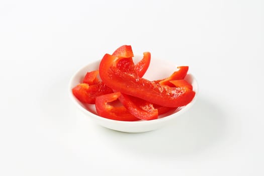 Thin slices of red bell pepper in white bowl